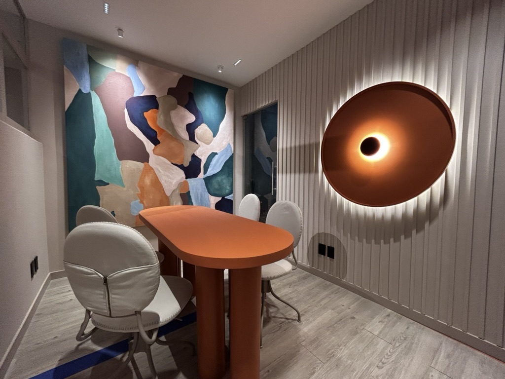 Sala de juntas con mural de colores, mesa terracota y lámpara circular
